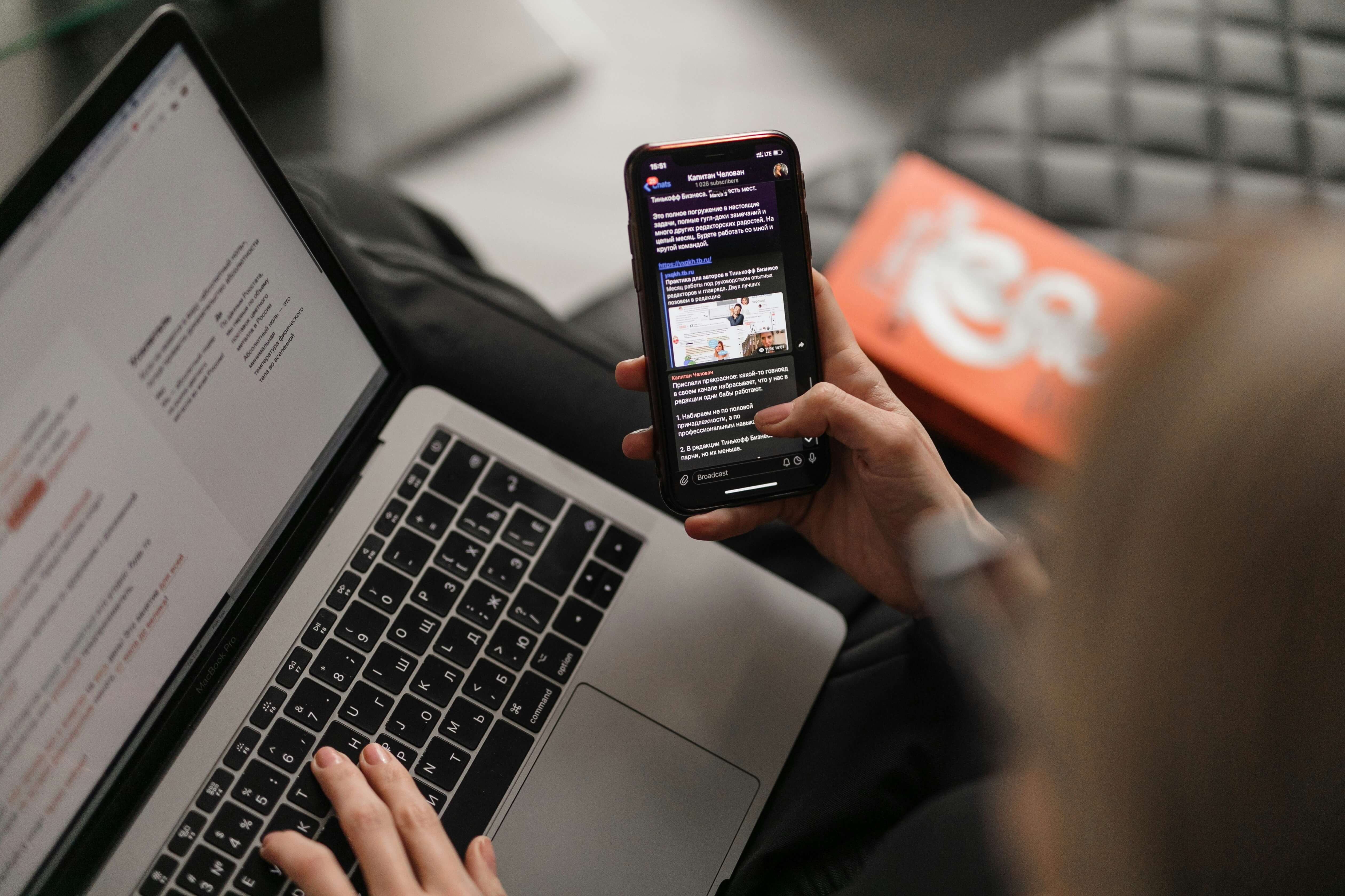 Person vergleicht Zahlen am Laptop und am Smartphone